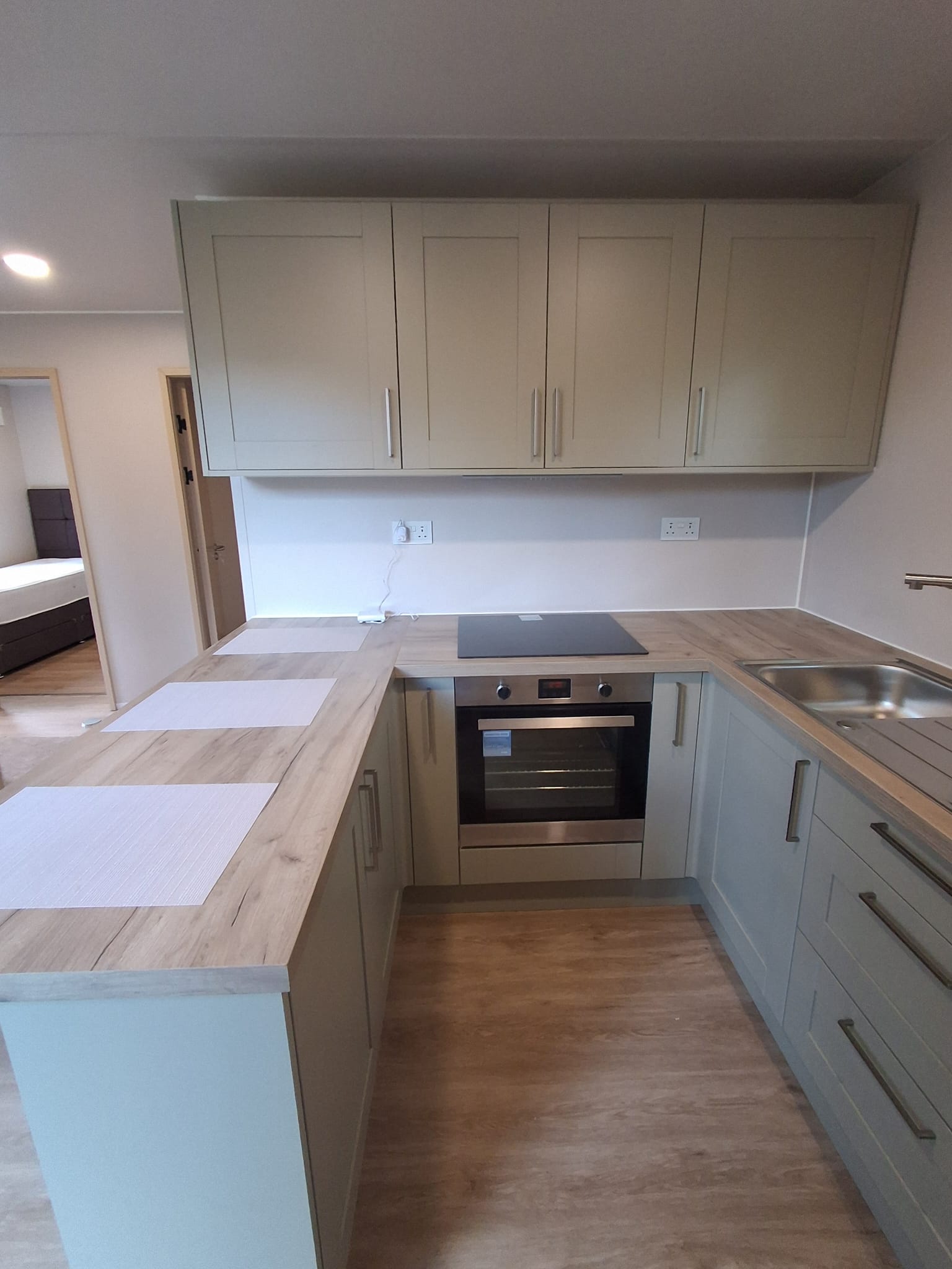 U shaped fitted kitchen with oven and hob, with a bedroom visible beyond