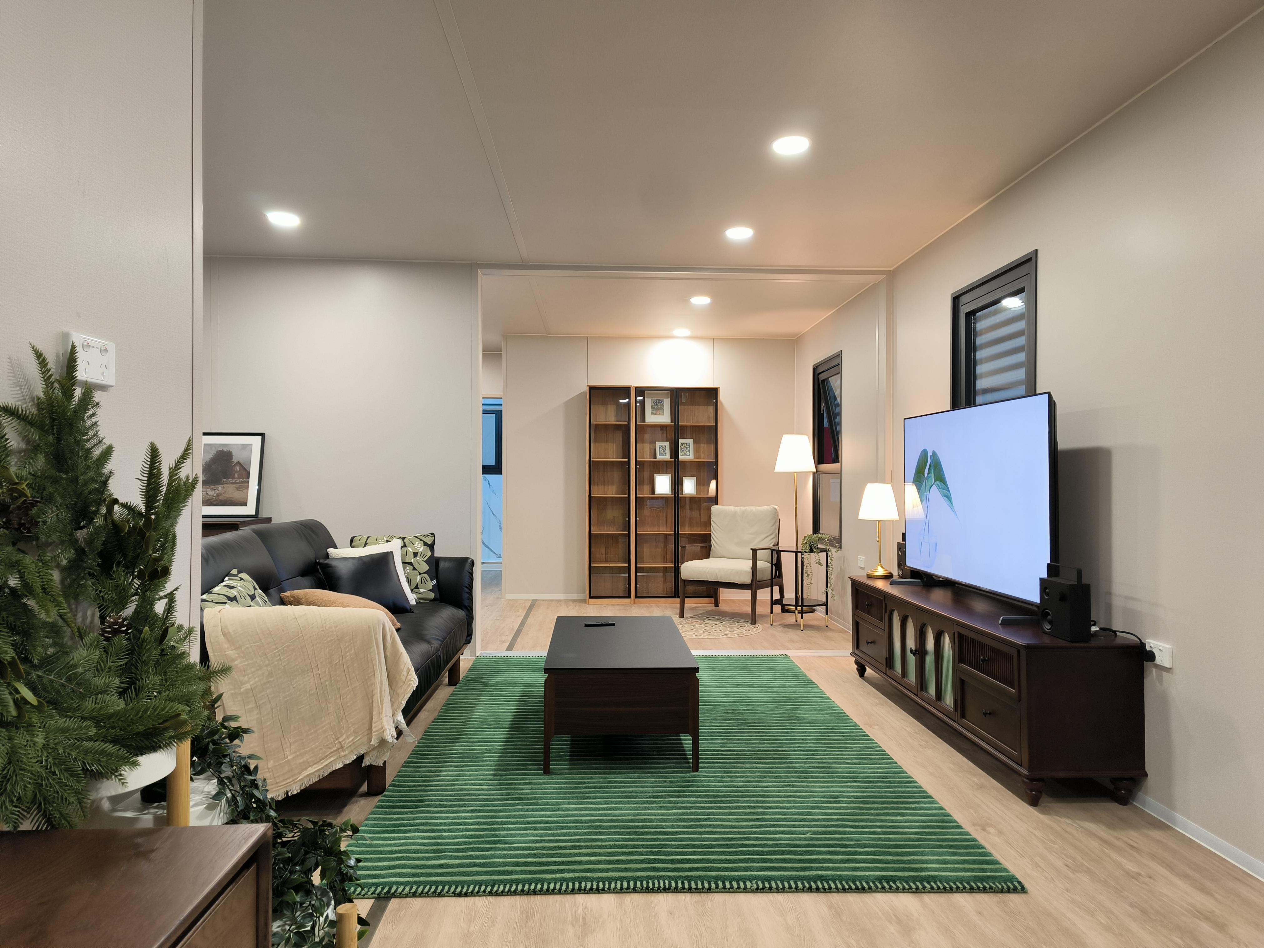 Open plan living room inside a PrefabX Flip Mix with sofa, media unit and dining area